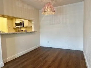 Unfurnished dining area featuring dark wood-look type flooring and a chandelier