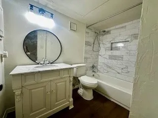 Bathroom featuring vanity, wood finished floors, tub / shower combination, and a textured wall