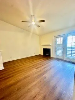 Unfurnished living room featuring a fireplace, wood finished floors, a ceiling fan, and lofted ceiling