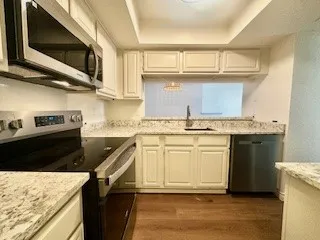 Kitchen with appliances with stainless steel finishes, a tray ceiling, dark wood-type flooring, and white cabinets