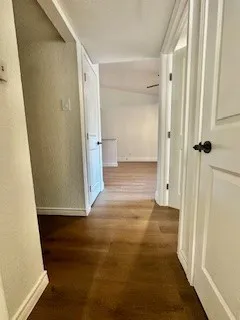 Corridor with wood look finished floors and a textured ceiling