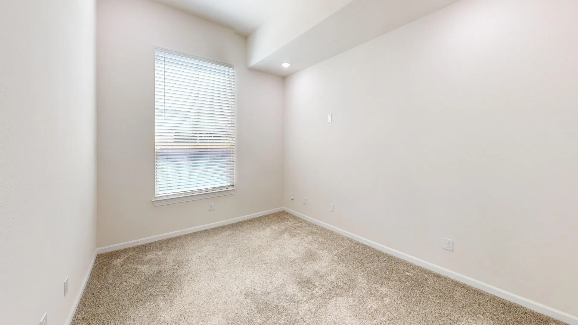 Neutral tone walls, recessed lighting, window with blinds, and carpeting