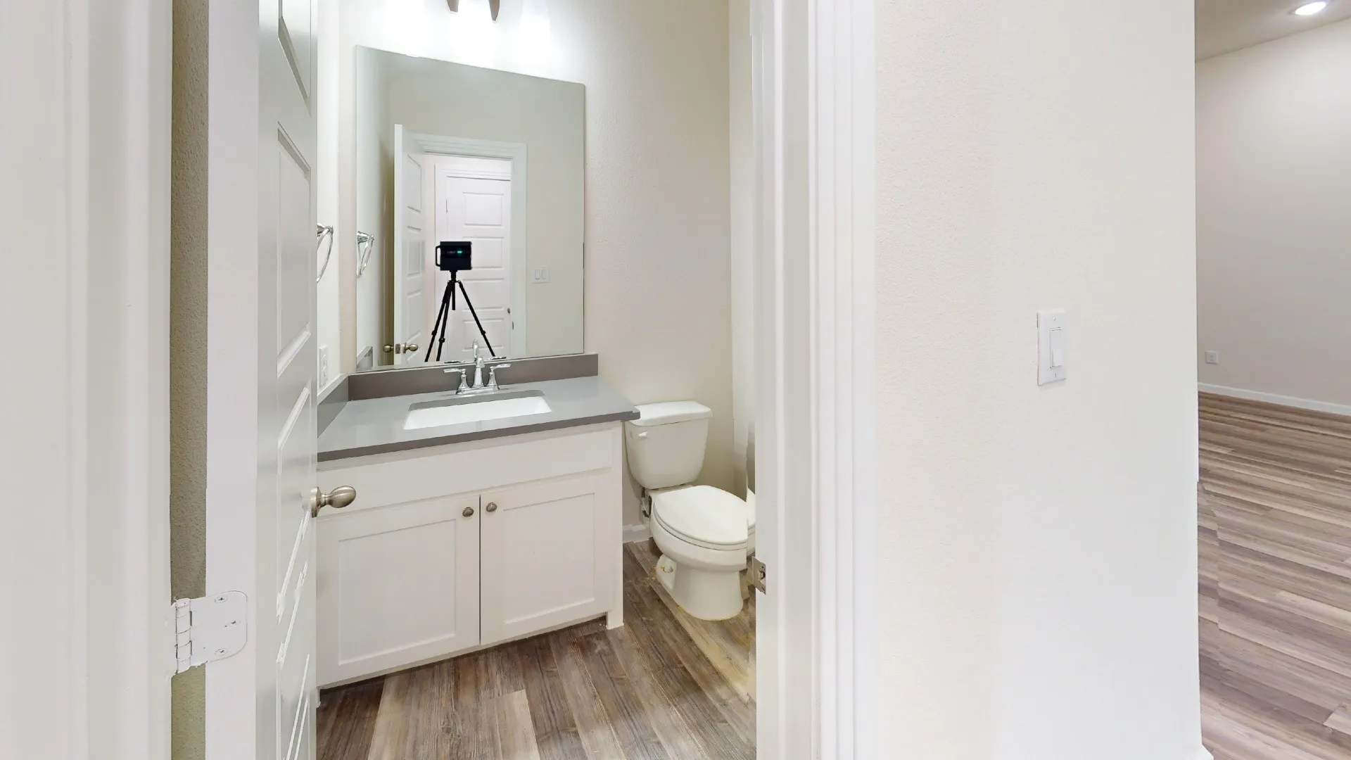White vanity with a rectangular sink, single-handle chrome faucet, and gray countertop
