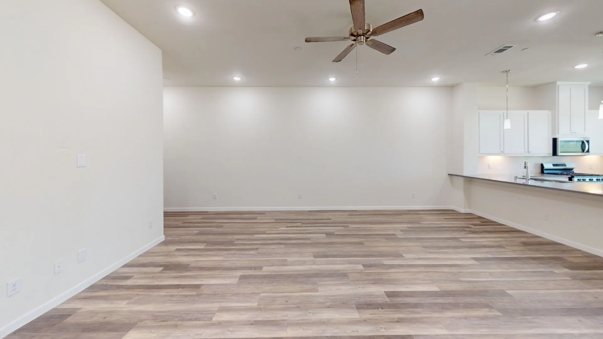 Open-concept living area with wood-finish flooring, recessed lighting, and a ceiling fan