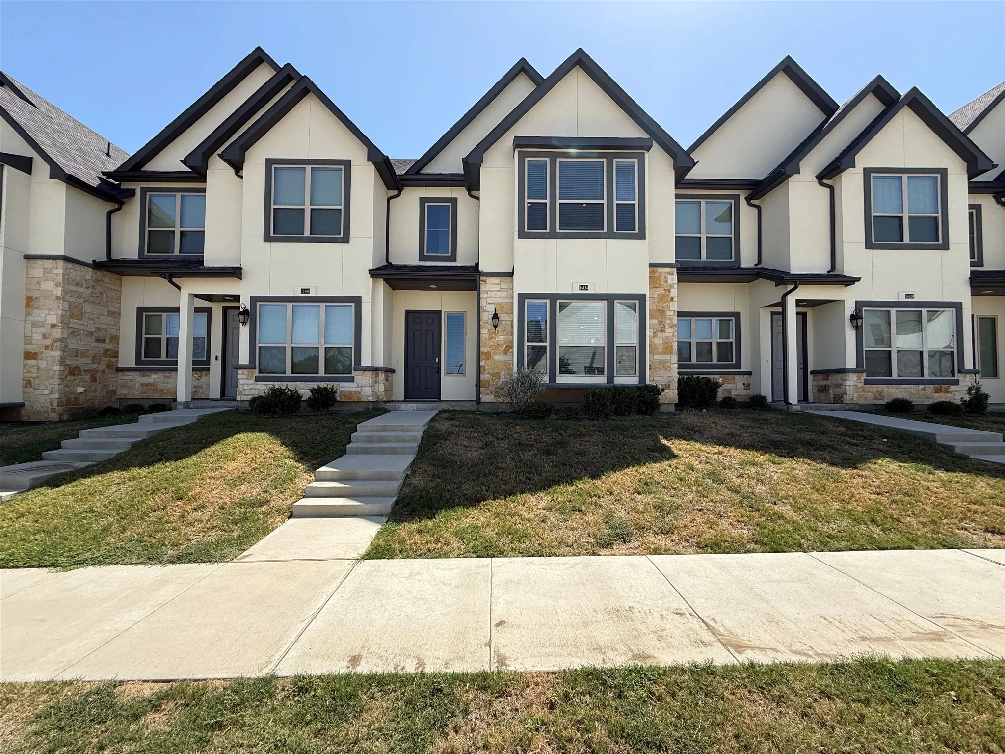 Contemporary townhome exterior featuring stone and stucco finishes