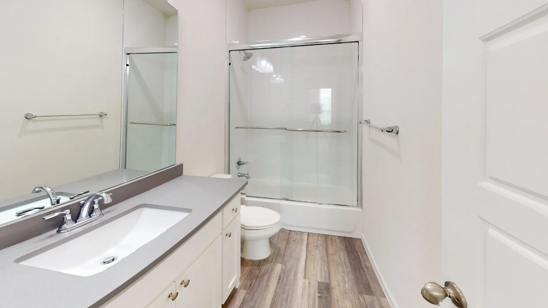 White vanity with chrome hardware, an integrated sink, and a gray countertop