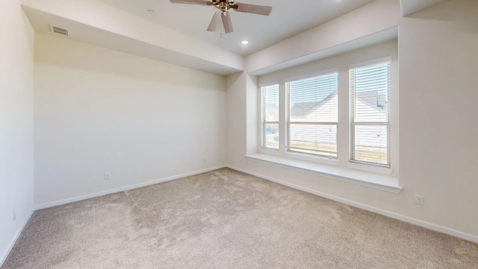 Expansive room with neutral carpeting and a wide window bench