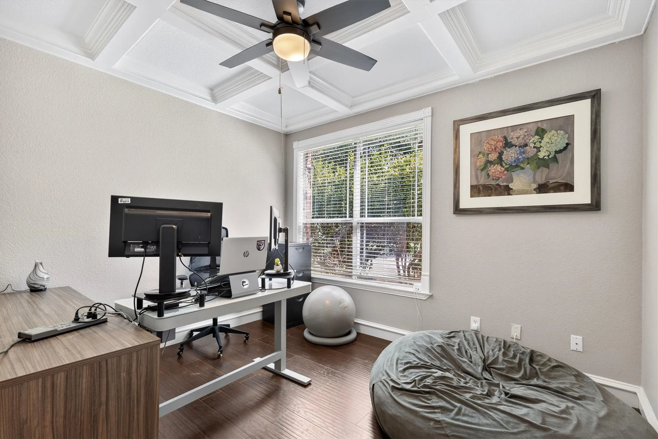 Coffered ceiling with a ceiling fan, wood-finish flooring, and a large window with blinds