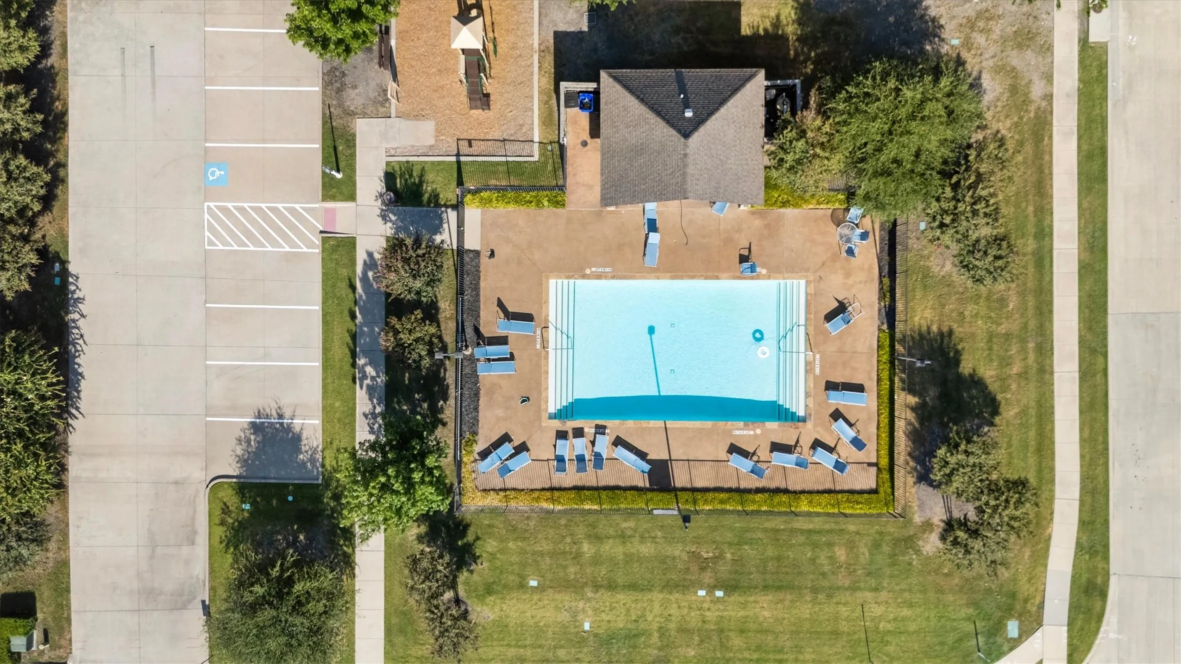 Community pool with integrated steps, surrounding paved deck, and adjacent building
