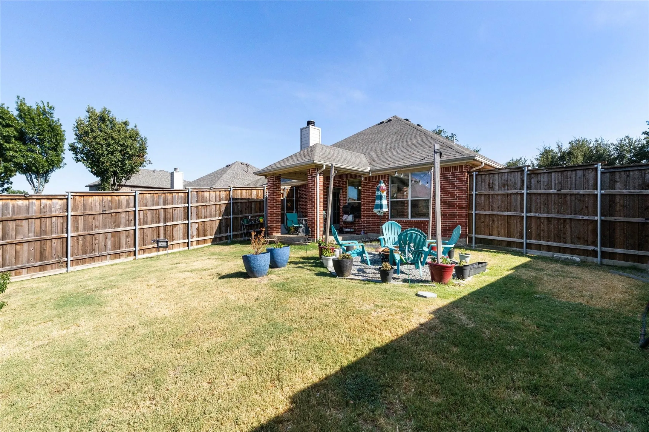 Private backyard with a covered patio, wood privacy fence, and brick exterior