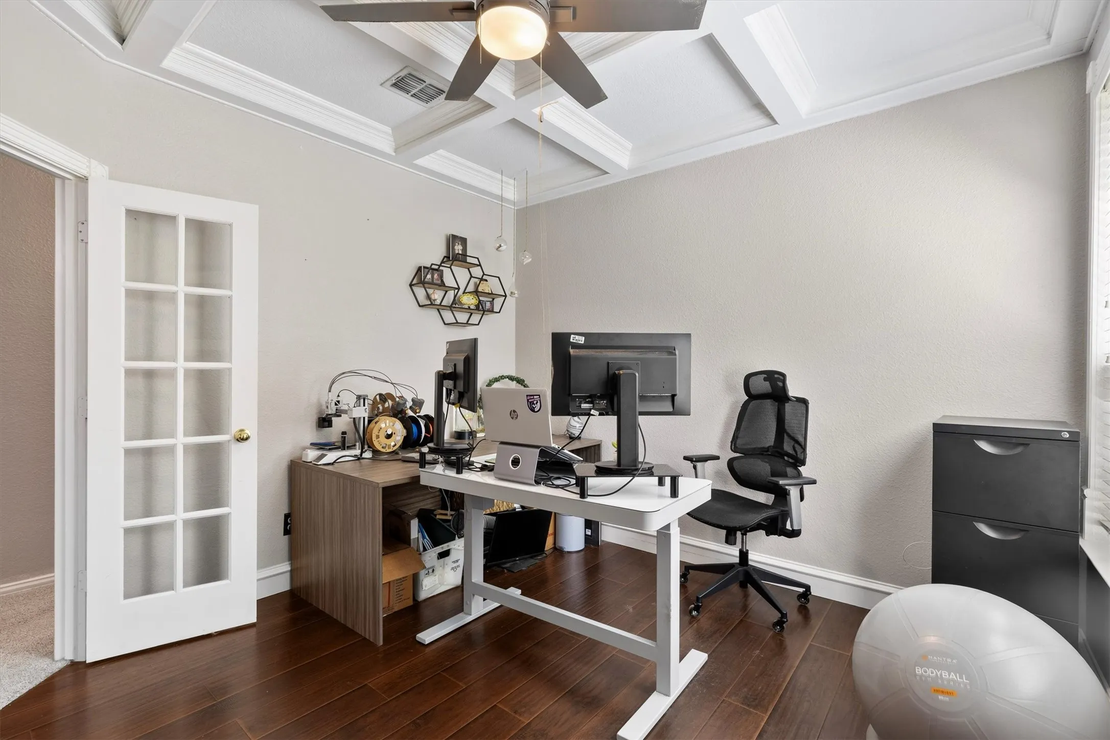 Coffered ceiling with a ceiling fan, French pane door, wood-finish flooring, and crown molding