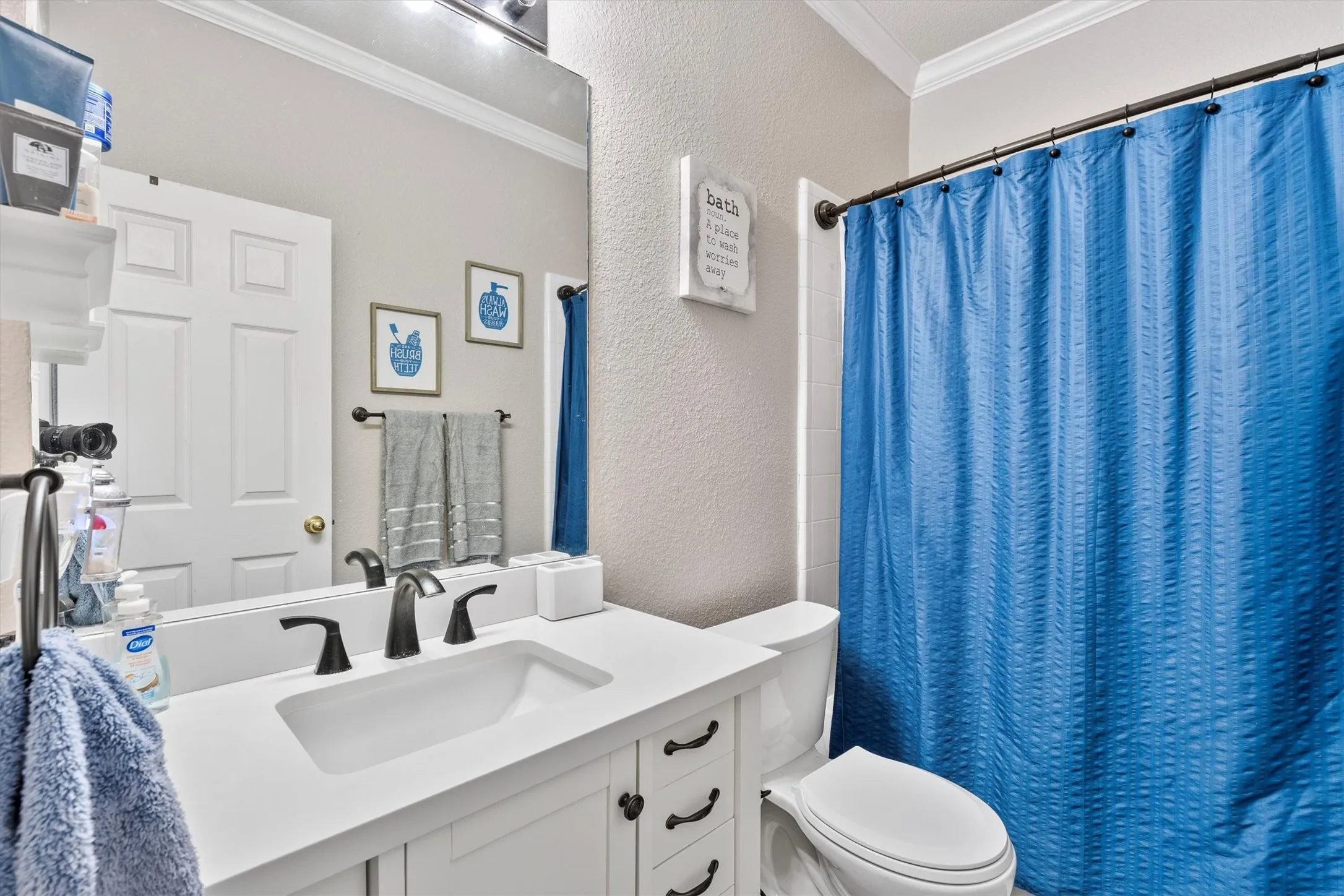 White vanity with integrated sink, dark bronze fixtures, crown molding, and a built-in toilet