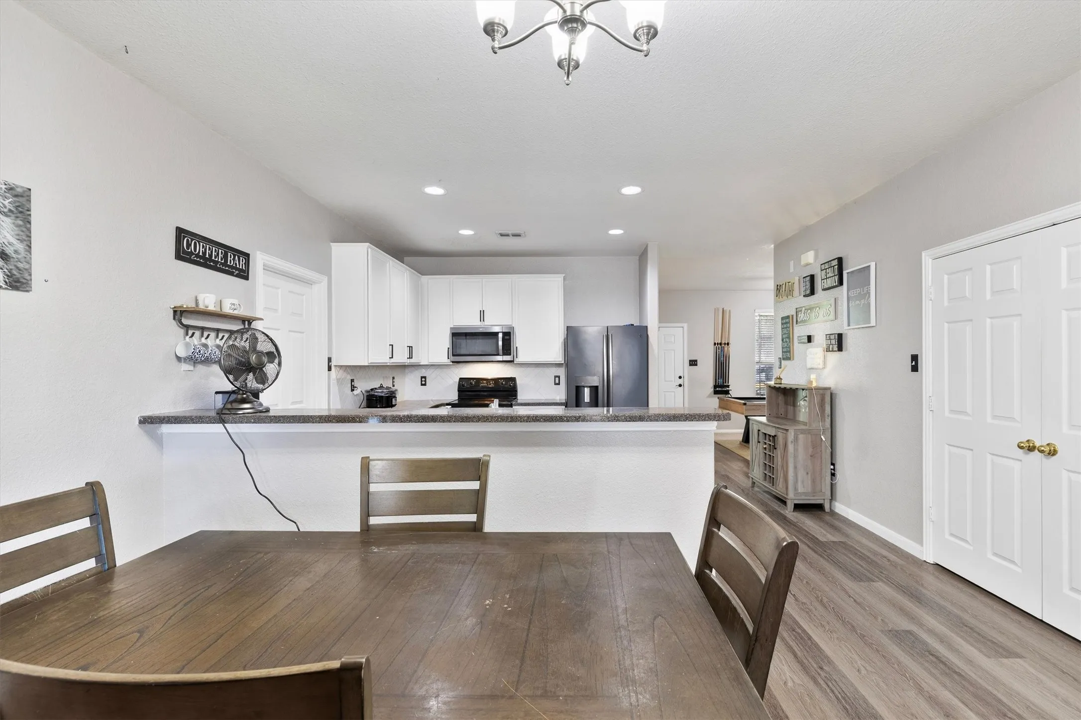 Open-concept living area featuring wood-finish flooring and a kitchen with white cabinetry