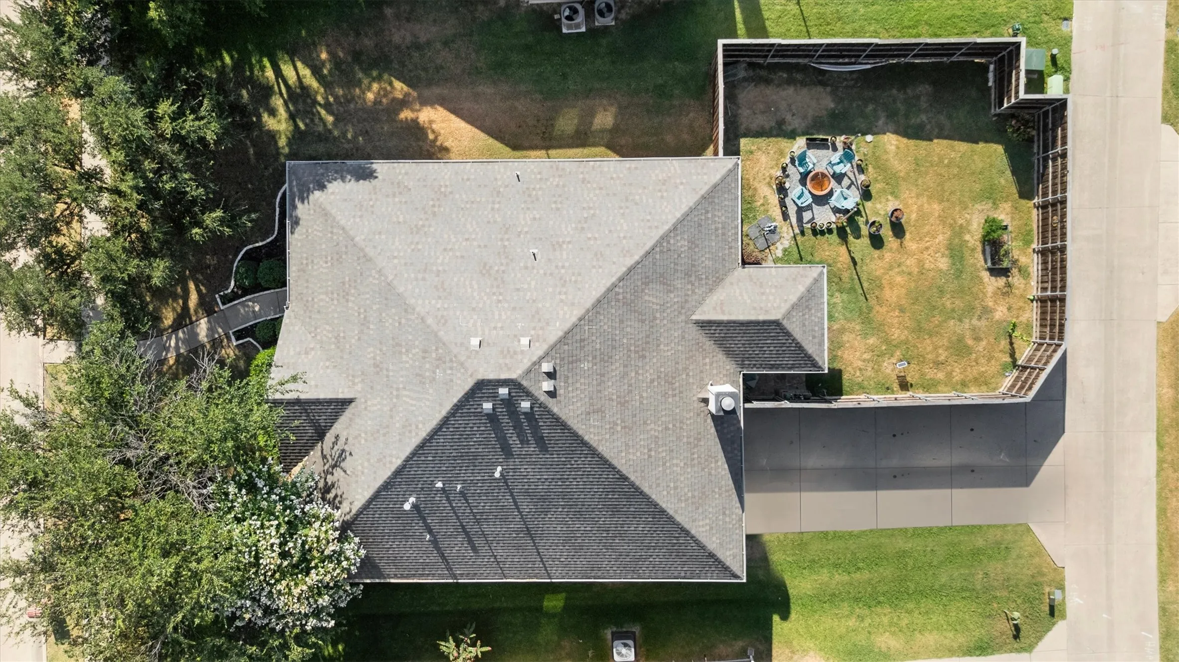 Pitched roof, concrete driveway, concrete patio, fenced backyard, and established trees