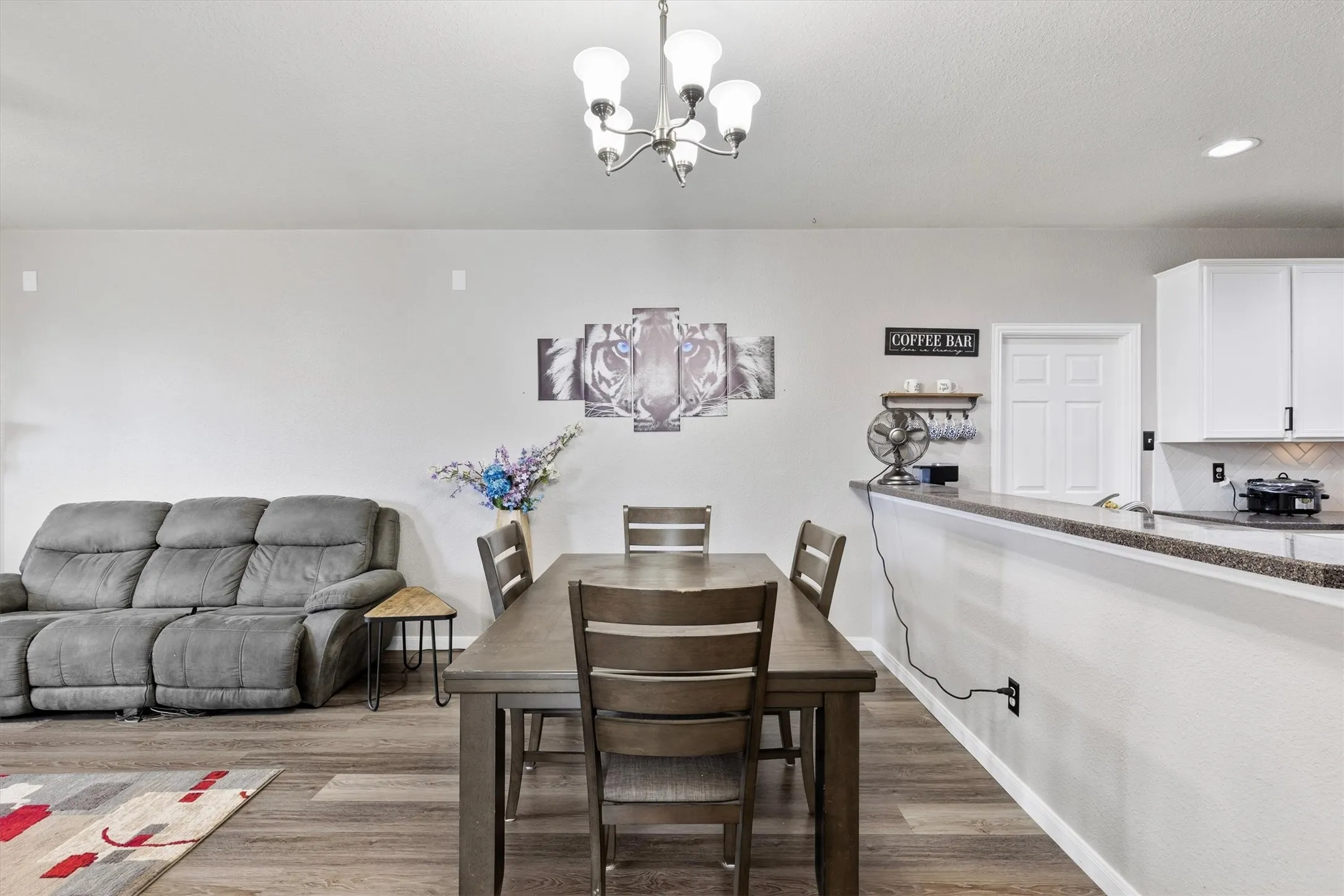 Open-concept living space with wood-finish flooring, a contemporary chandelier, and a breakfast bar with an integrated countertop
