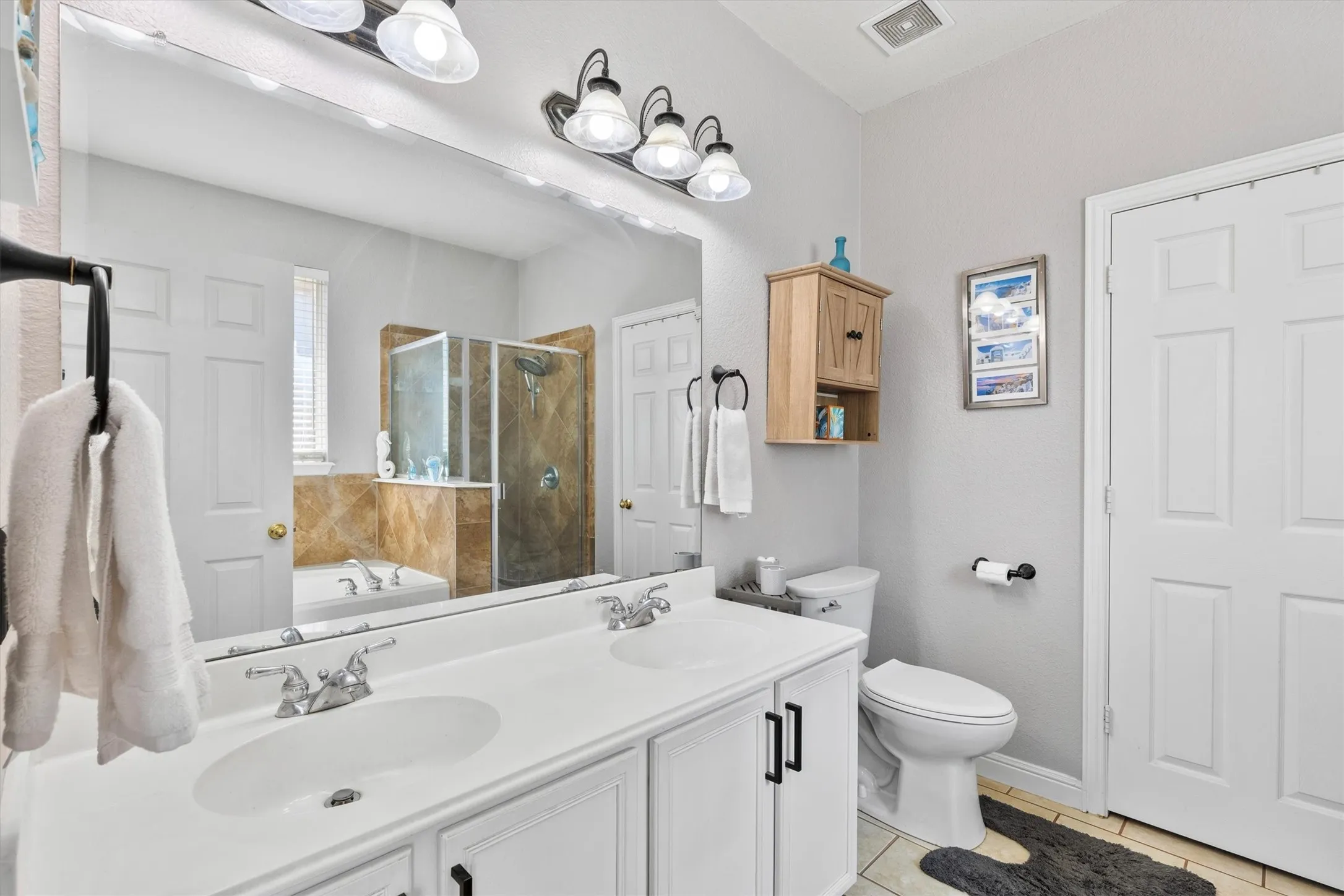 Double vanity with white countertop, chrome faucets, and white cabinetry