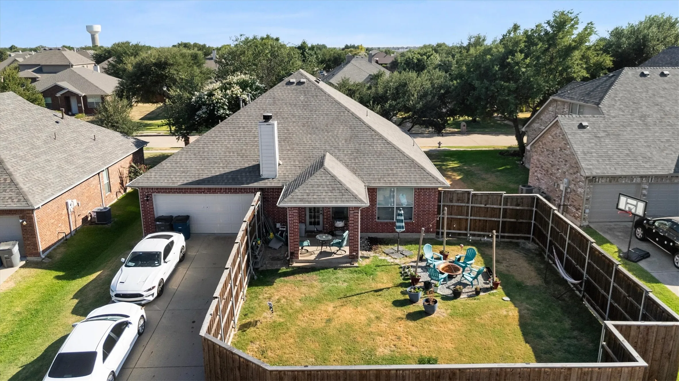 Brick exterior with an attached garage, featuring a private fenced backyard with a patio