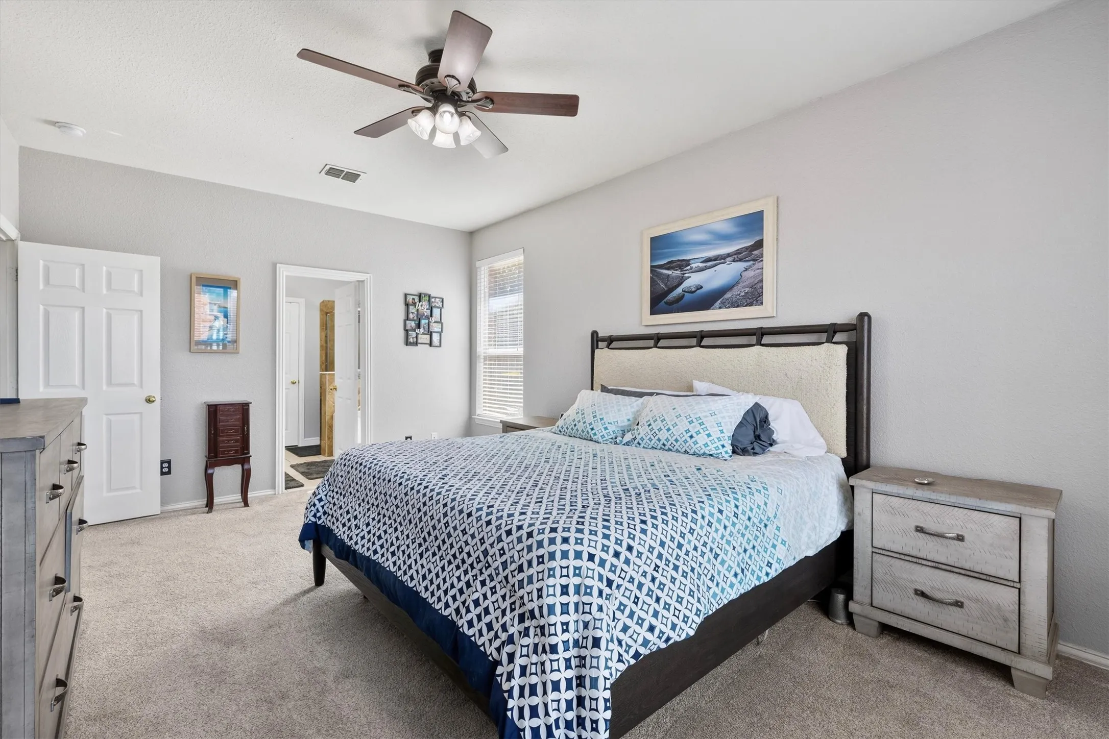 Tray ceiling, ceiling fan with light fixture, light-toned carpeting, white interior doors, and a window with blinds