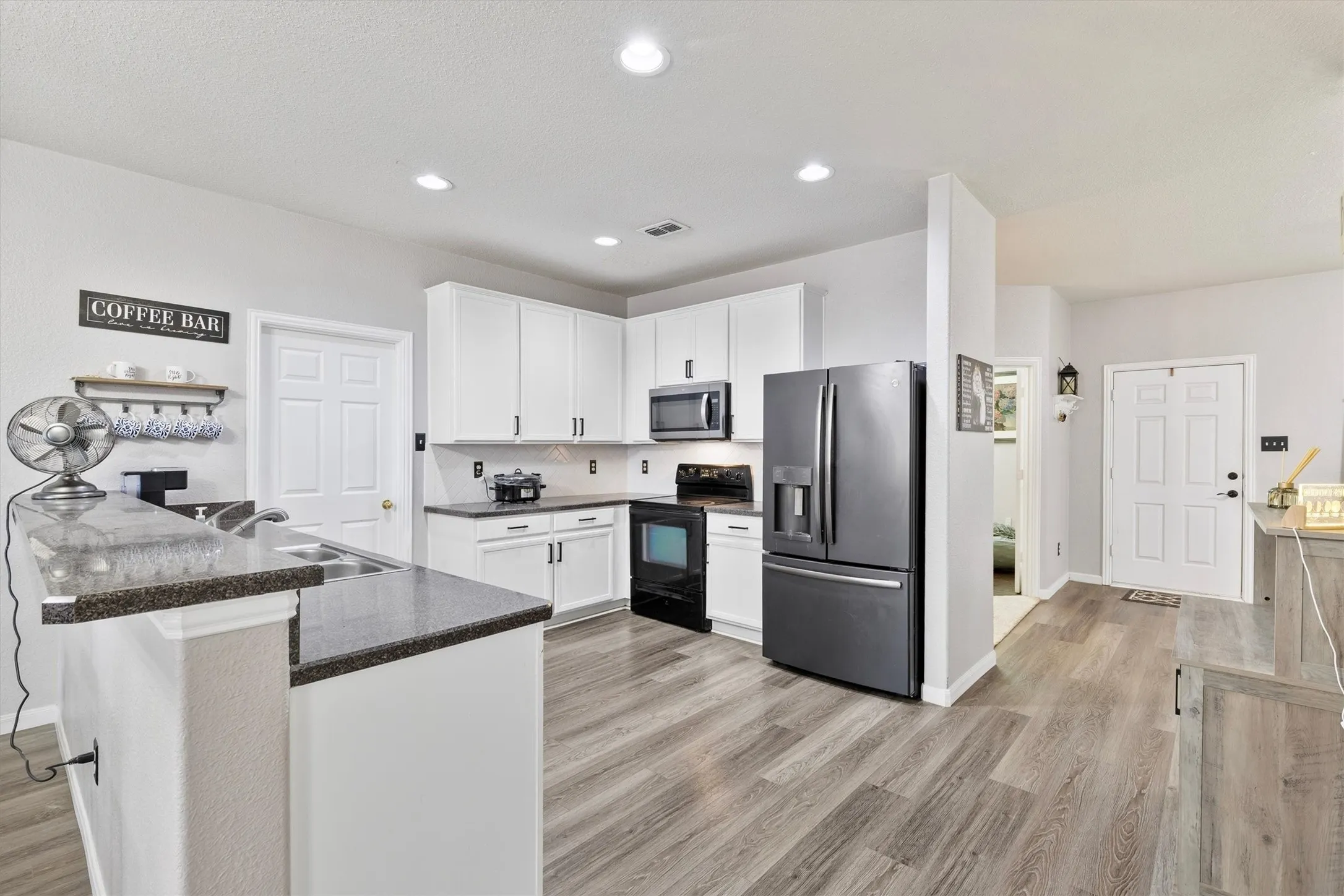 Kitchen featuring wood-finish flooring, white cabinetry, dark countertops, and recessed lighting