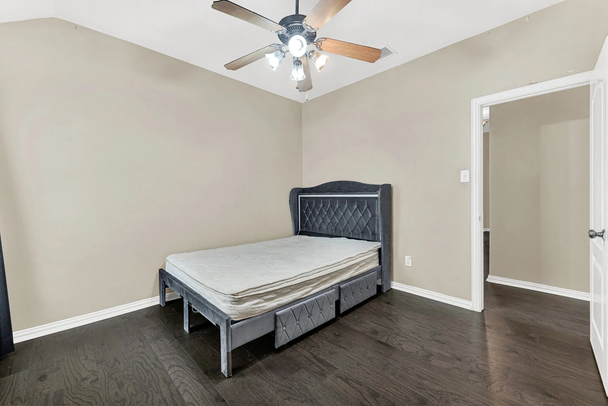 Dark wood-finish flooring, light neutral wall paint, white trim, and a ceiling fan with integrated lighting