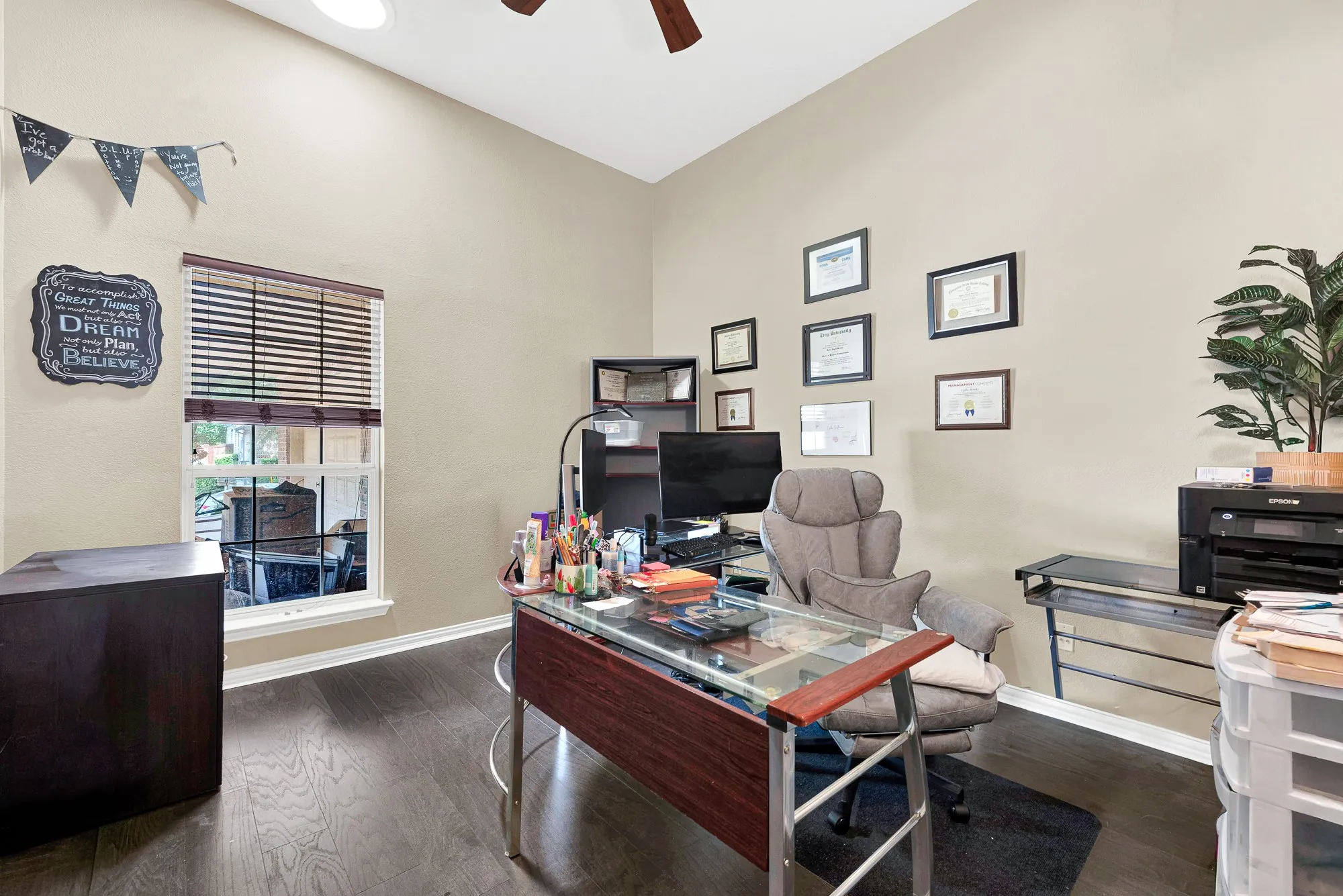 Vaulted ceiling with an attached ceiling fan, large window with blinds, wood-finish flooring, and neutral wall tones