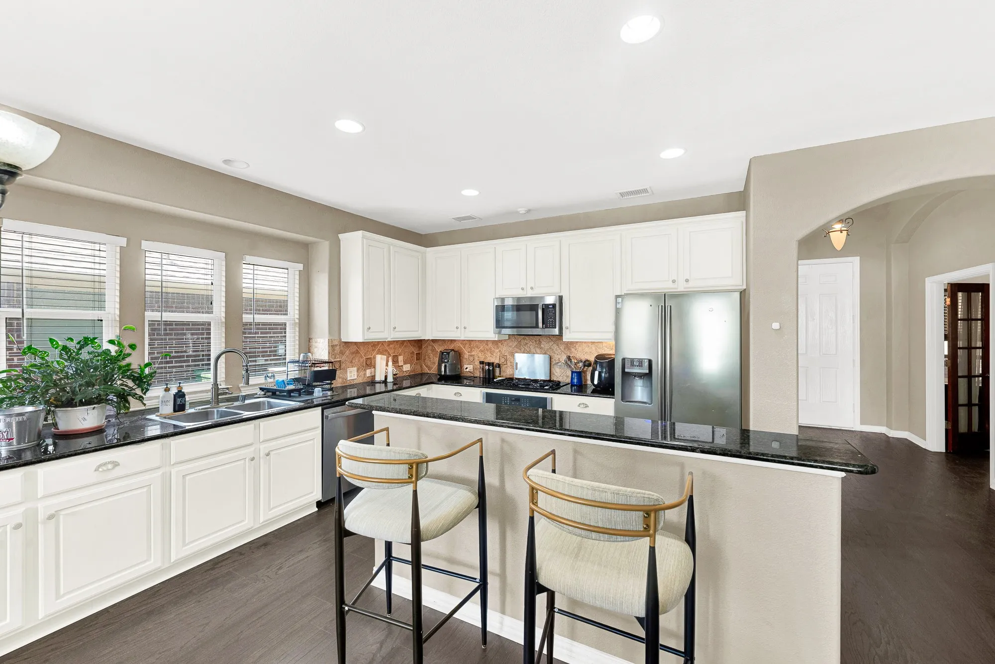 Kitchen featuring white cabinetry, dark countertops, stainless steel appliances, and wood-finish flooring
