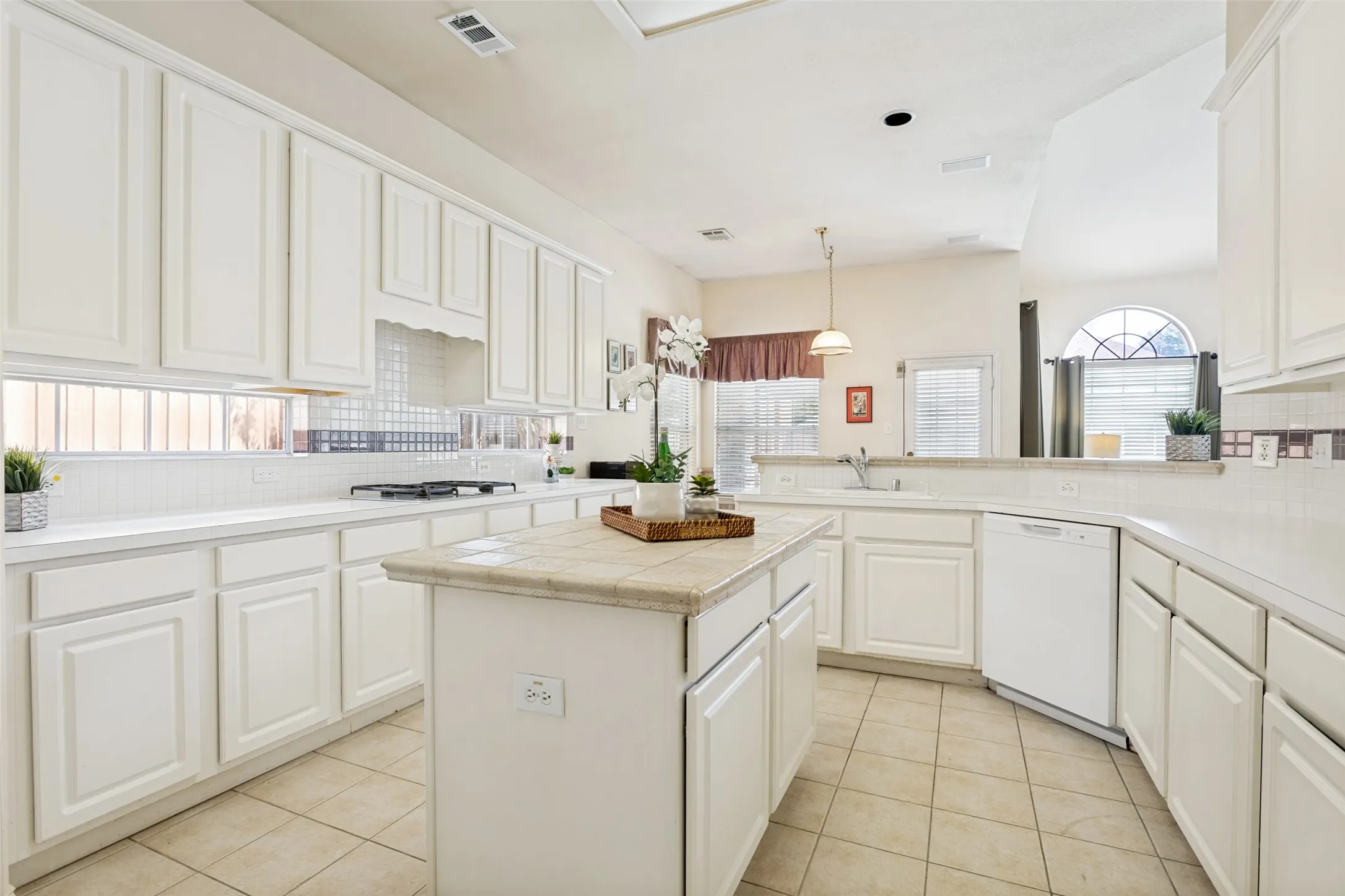 Kitchen is large and bright with a prep island and gas cooktop.