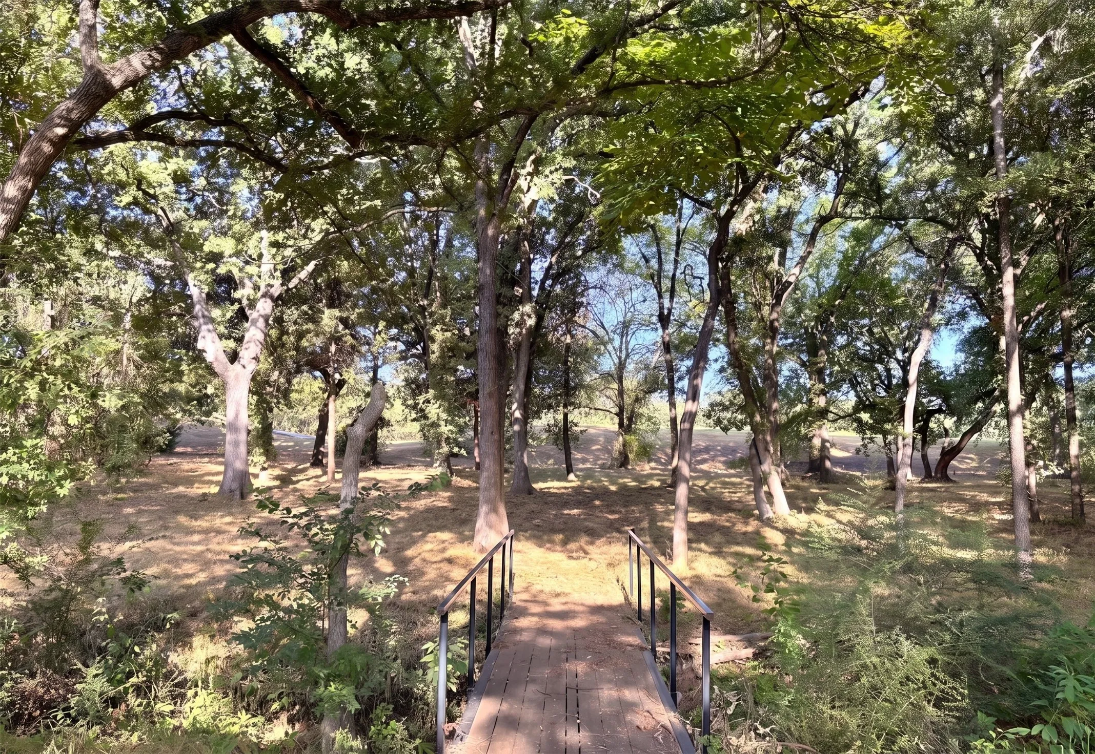 Mature trees and lush grounds frame a picturesque creek, where a private bridge opens to beautiful golf course views