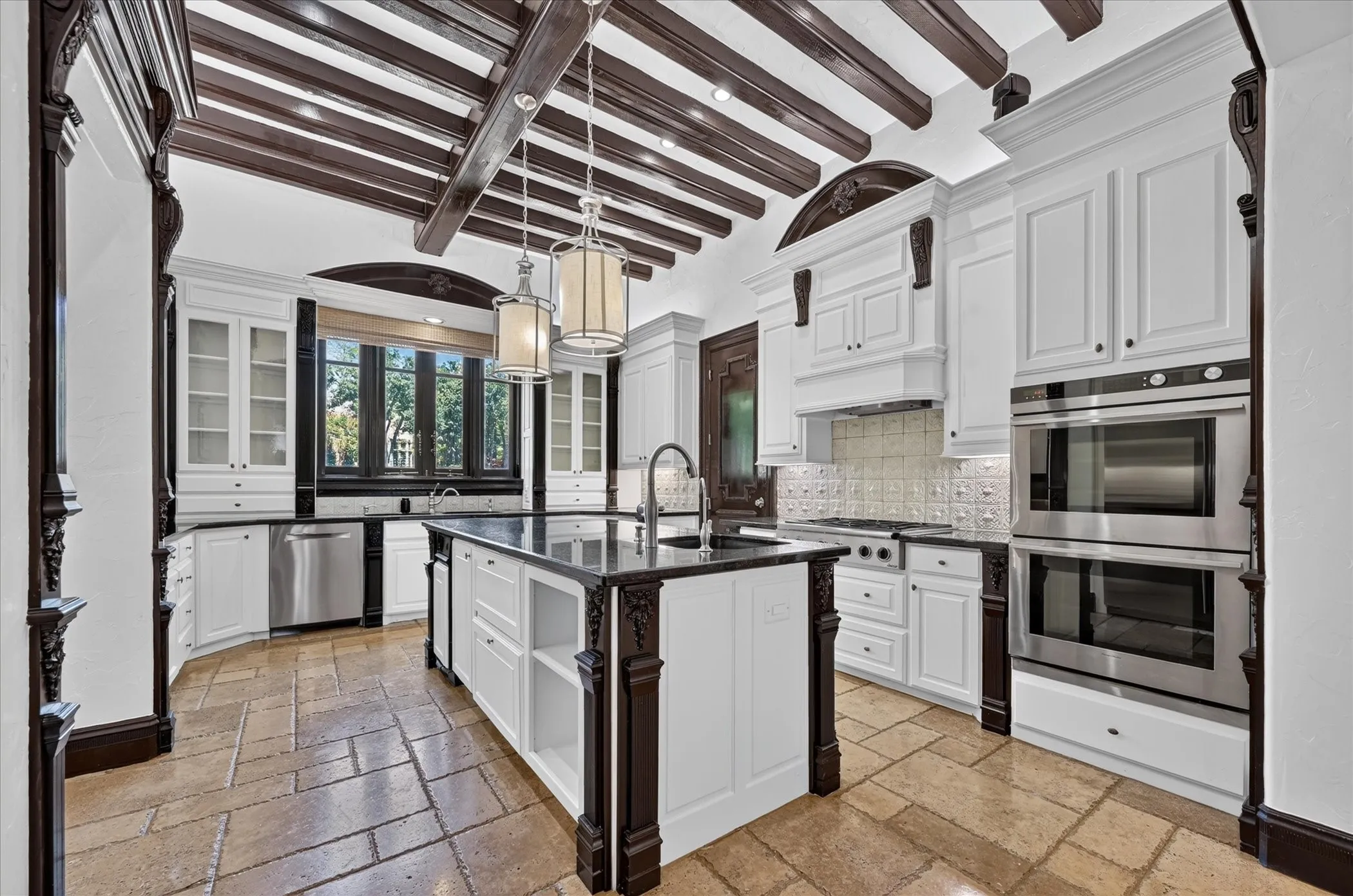 The chef’s kitchen is equipped with granite counters, high-end stainless steel appliances, a built-in coffee maker, dual dishwashers, an island with prep sink, butler’s pantry, and walk-in pantry.