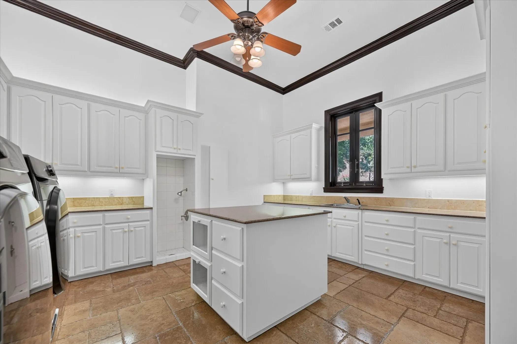 A massive laundry room is thoughtfully designed with abundant cabinetry, a pet washing station, and a built-in ironing board.