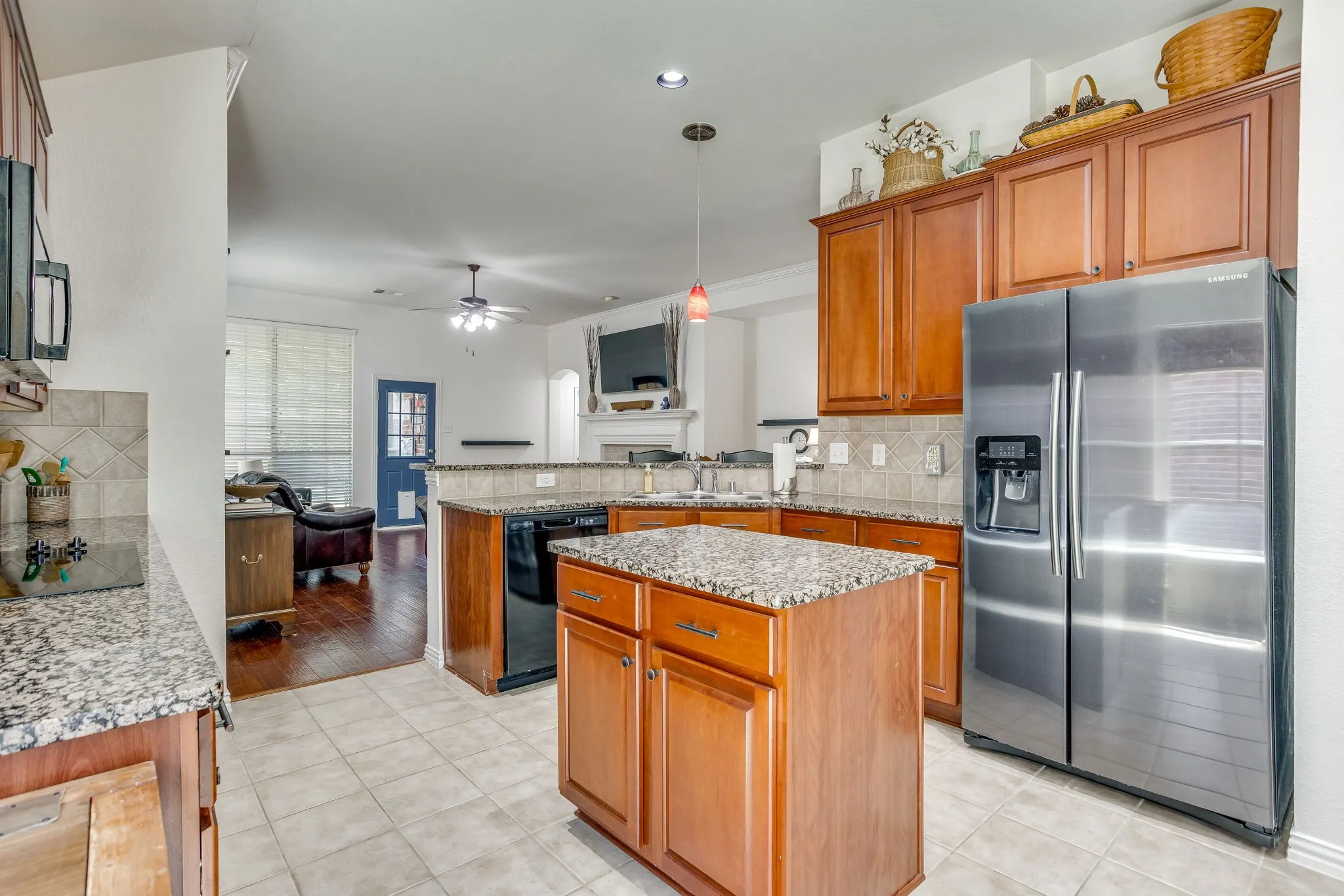 Kitchen featuring granite countertops, wood cabinetry, tile flooring, and a stainless steel side-by-side refrigerator