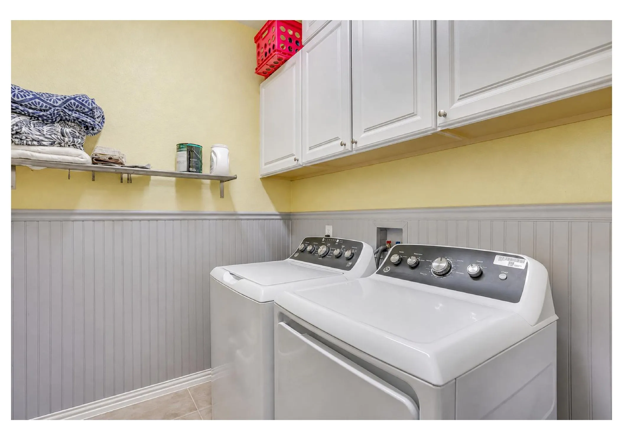 White shaker-style cabinetry, beadboard wainscoting, and tile flooring.  Edited photo with AI