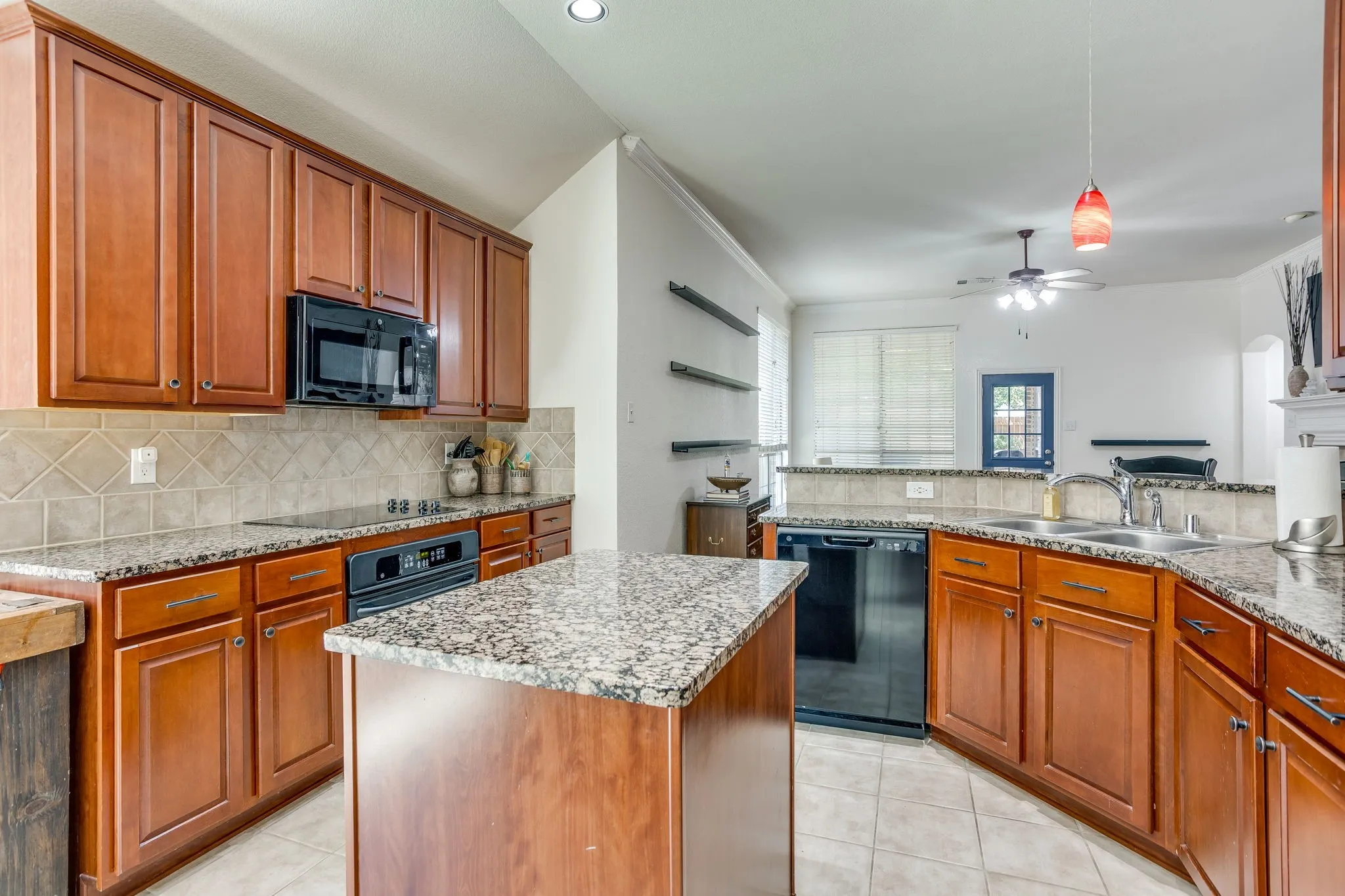 Kitchen featuring wood cabinetry, granite countertops, tile flooring, a built-in microwave, and a black dishwasher