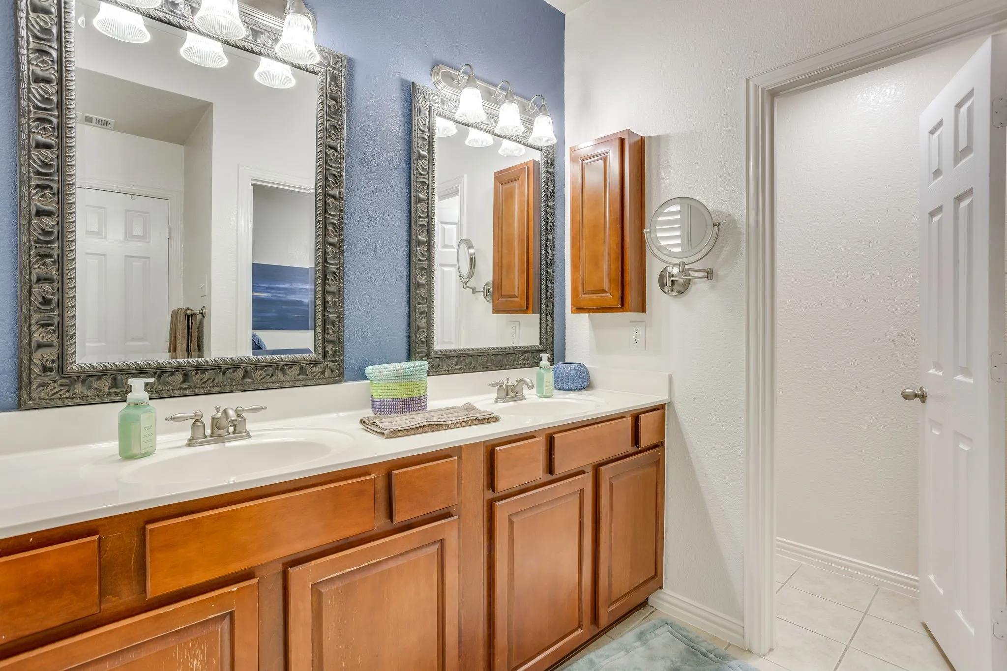 Dual vanity with white countertops, integrated sinks, and wood cabinetry