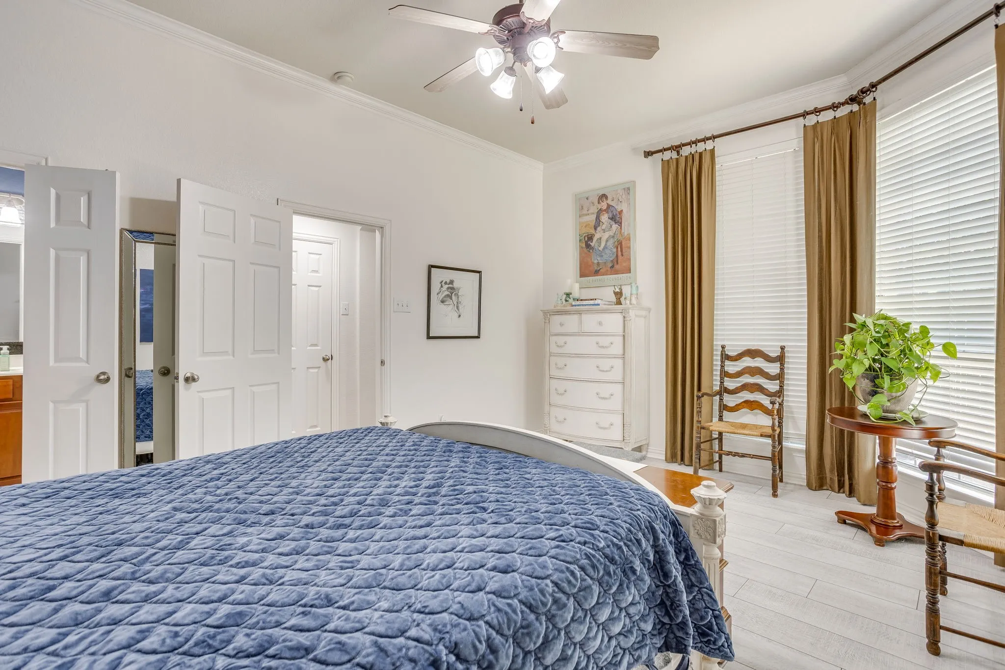 White-painted paneled doors, ceiling fan with integrated lighting, vinyl wood flooring, and bay window with blinds