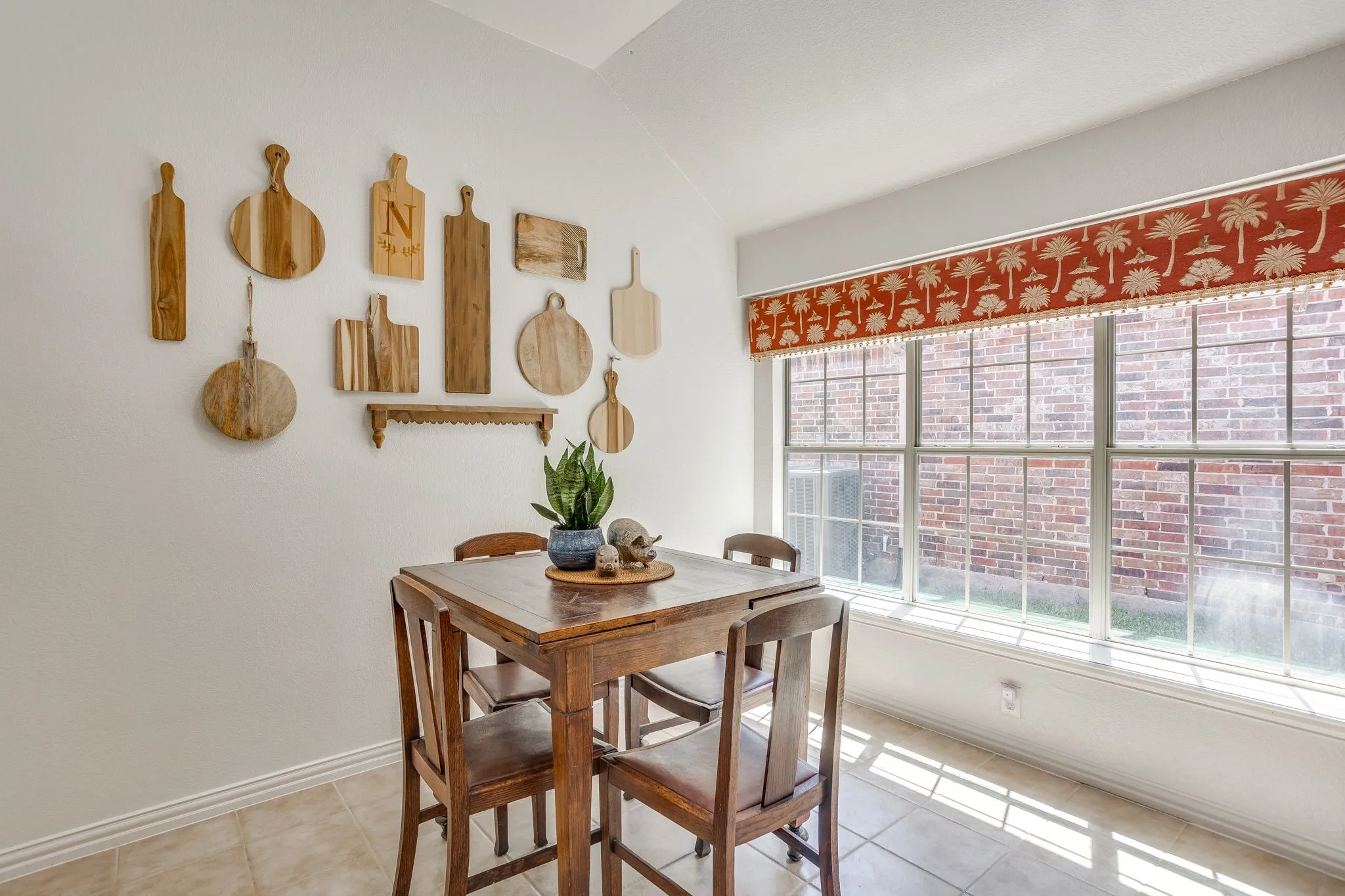Vaulted ceiling, tiled flooring, expansive window, window valance, and white walls