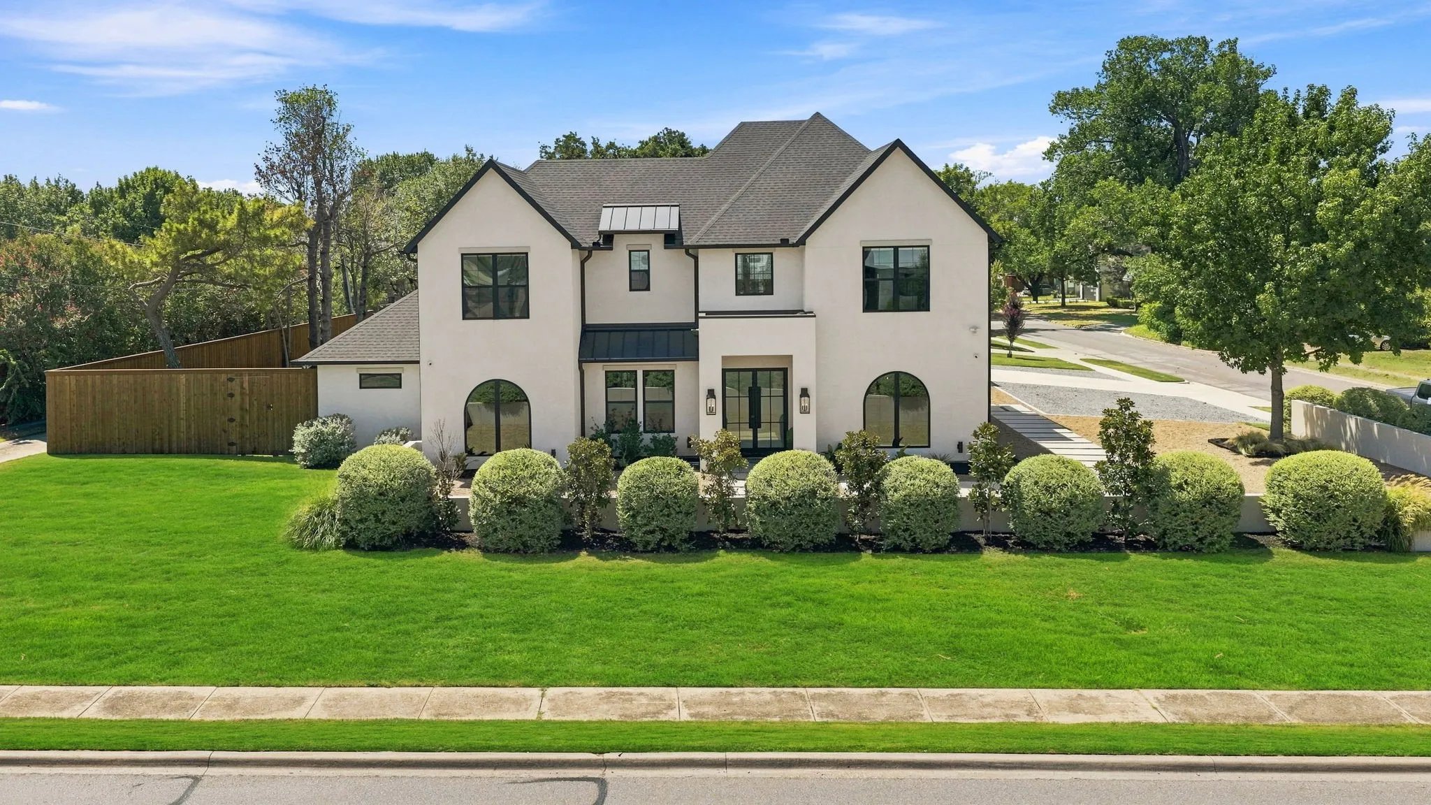 Stucco exterior with black-framed windows, arch-top windows, and a dark shingled roof