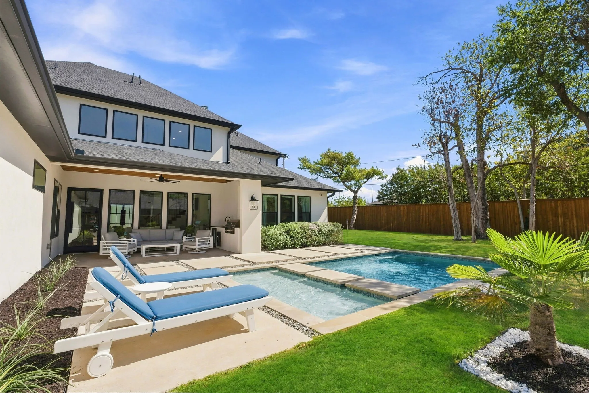 Lounge next to the expansive backyard featuring a rectangular swimming pool, integrated spa, and a covered patio with recessed lighting
