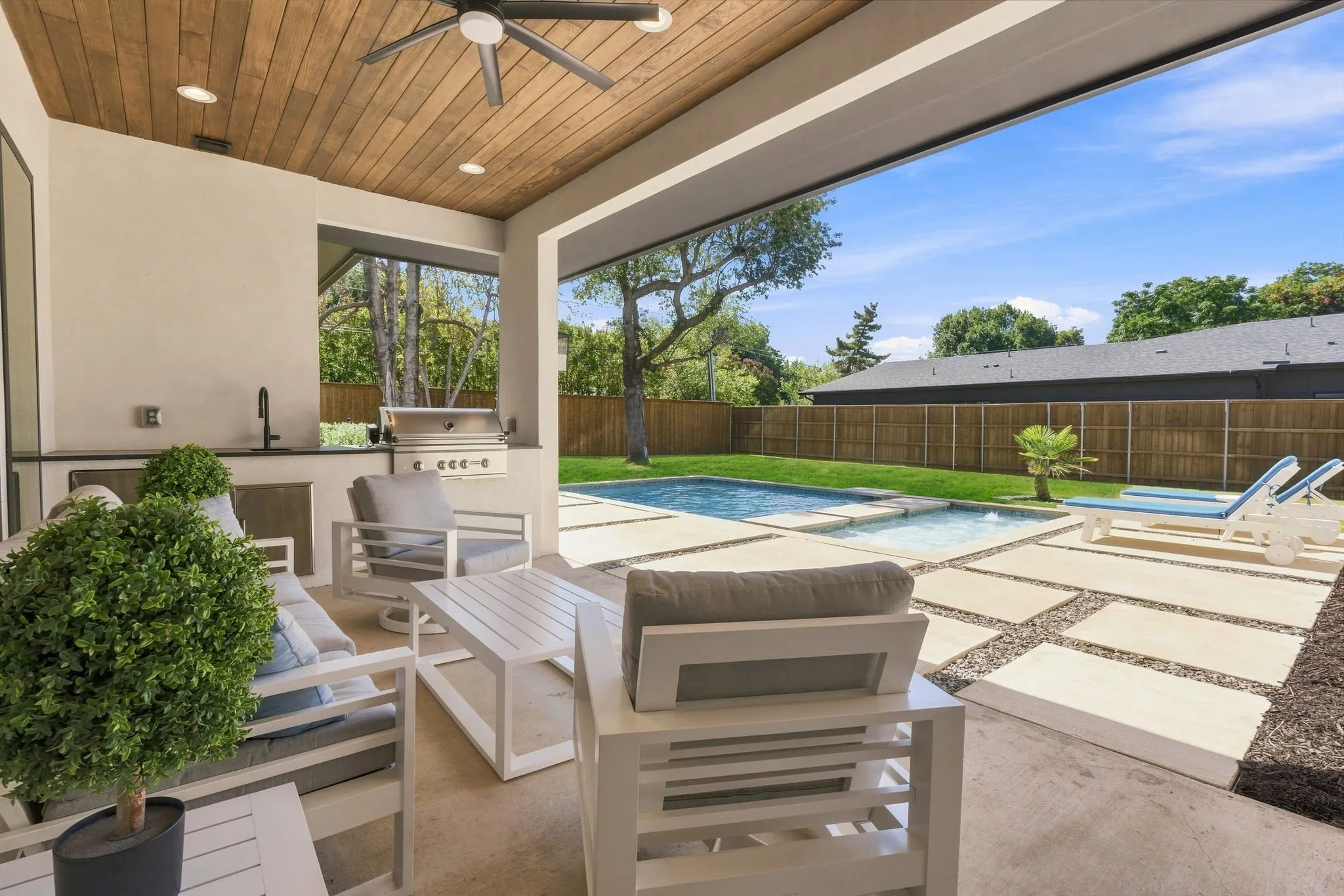Covered patio with wood-finish ceiling, built-in outdoor kitchen, concrete patio flooring, inground swimming pool, and a fenced yard