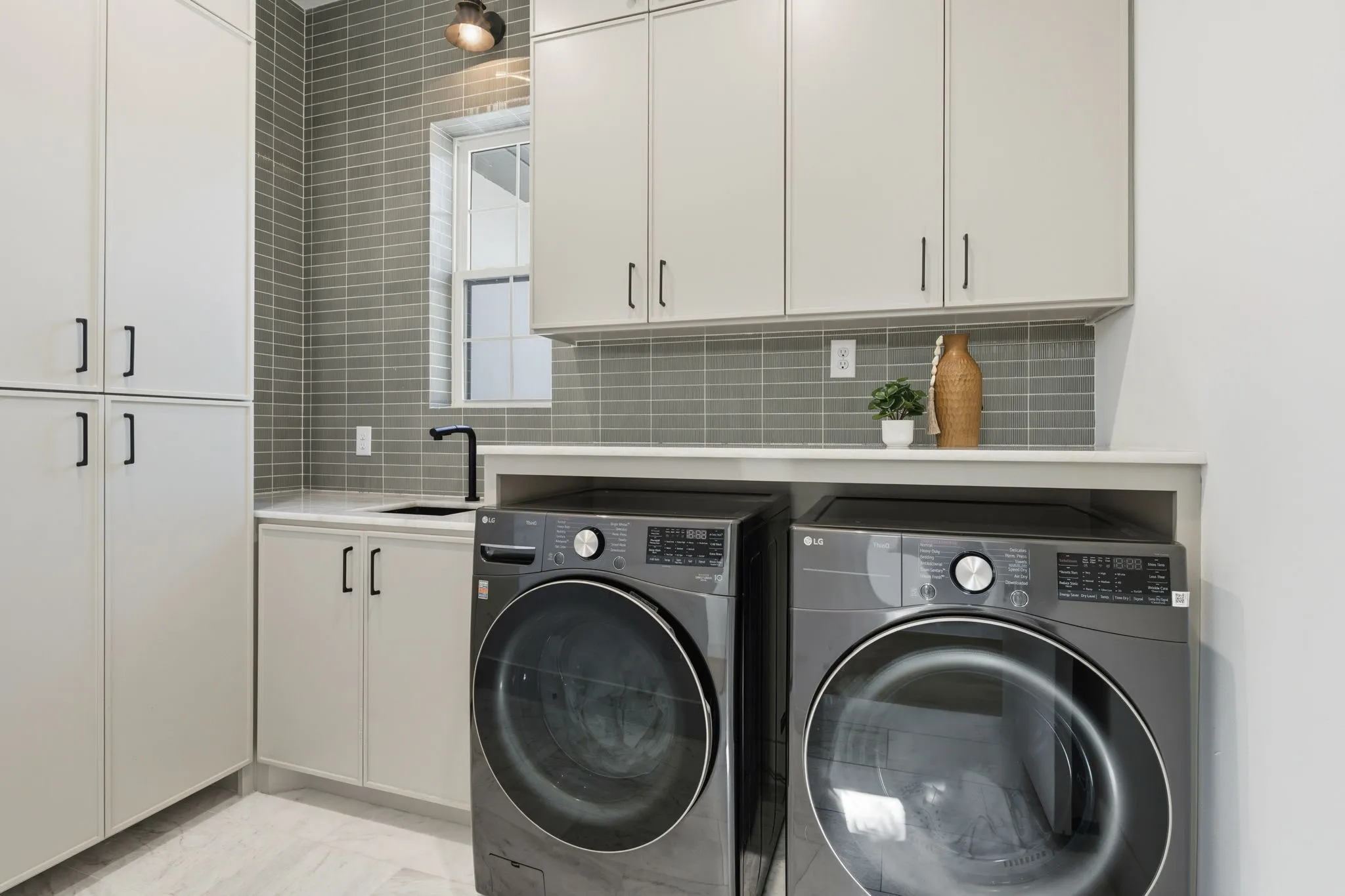 Built-in cabinetry, subway tile backsplash, under-mount sink with matte black faucet, and light-toned countertop