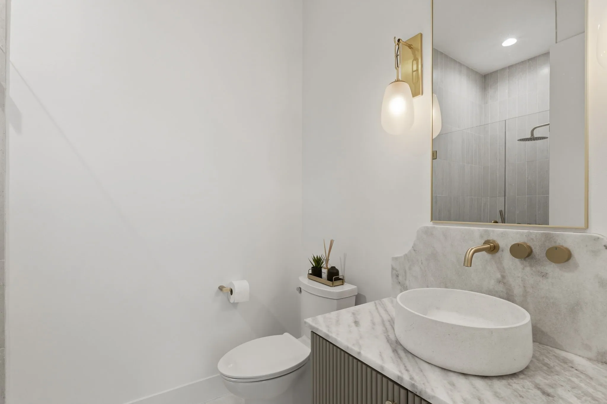 Vanity featuring a vessel sink, wall-mounted faucet, and marble countertop