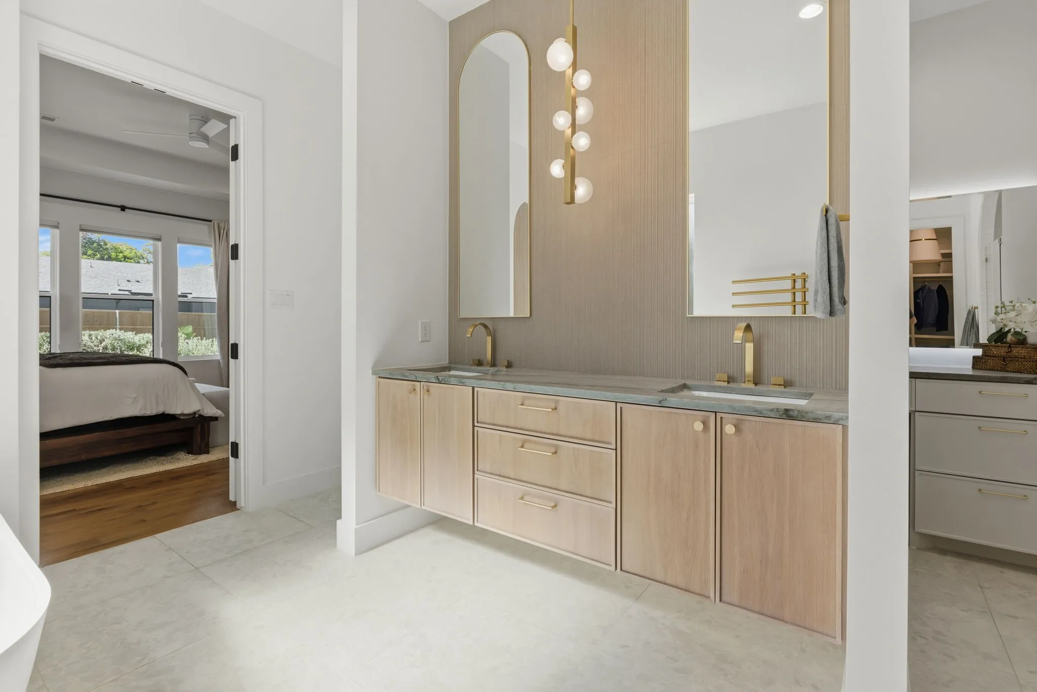 Floating double vanity with integrated sinks, gold-finish fixtures, and a decorative wall-mounted light fixture