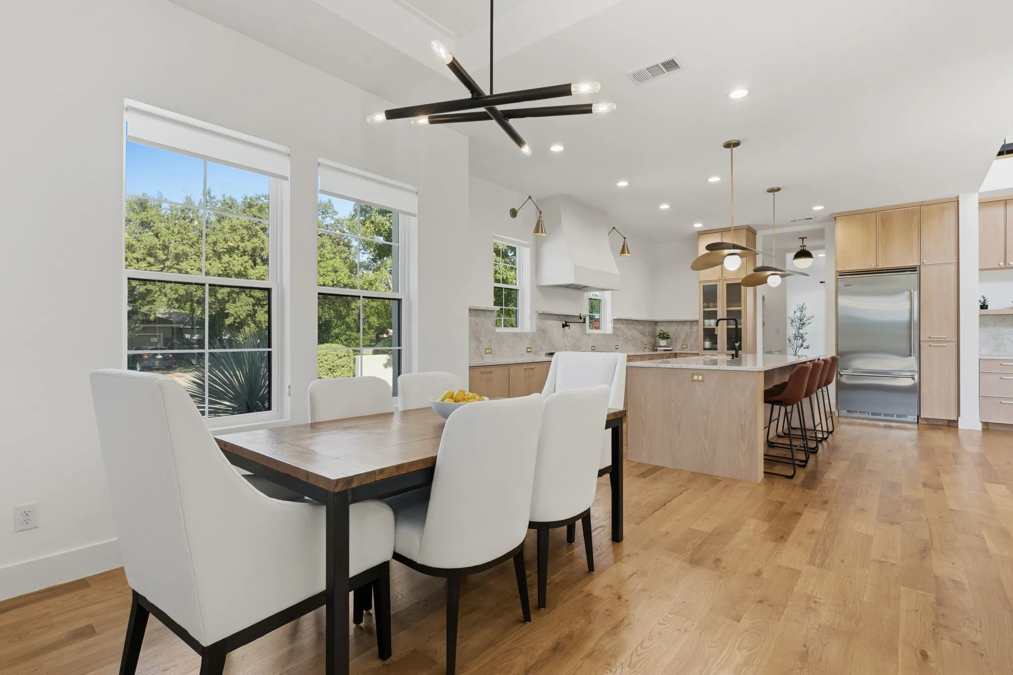 Spacious open-concept interior with wood-finish flooring, multiple windows, and recessed lighting