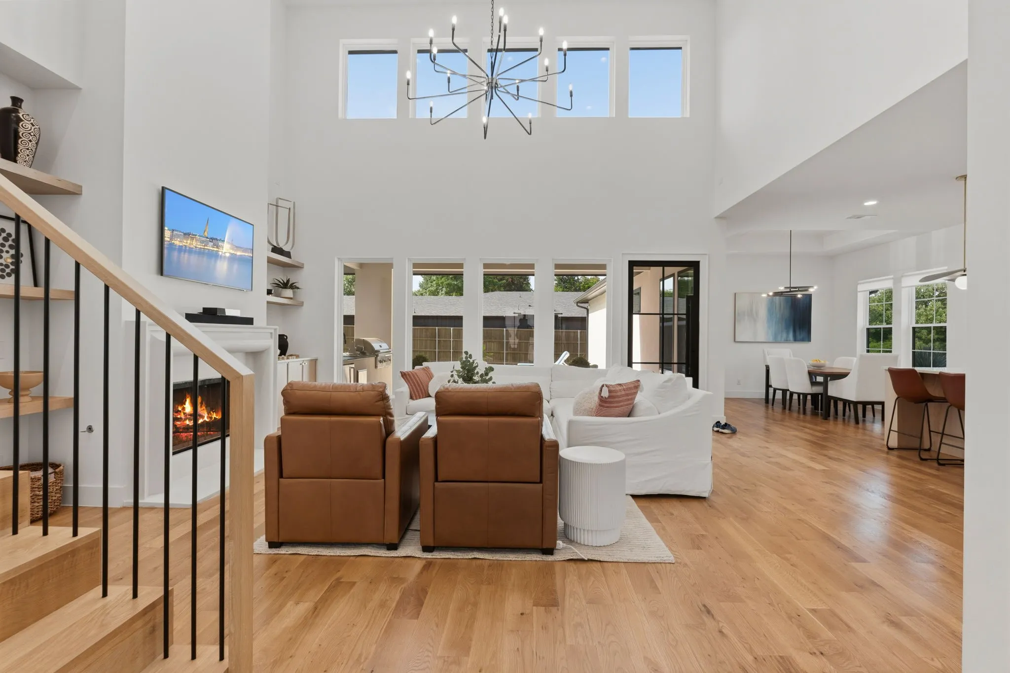Two-story living area featuring a fireplace, wood-finish flooring, a contemporary chandelier, and high windows