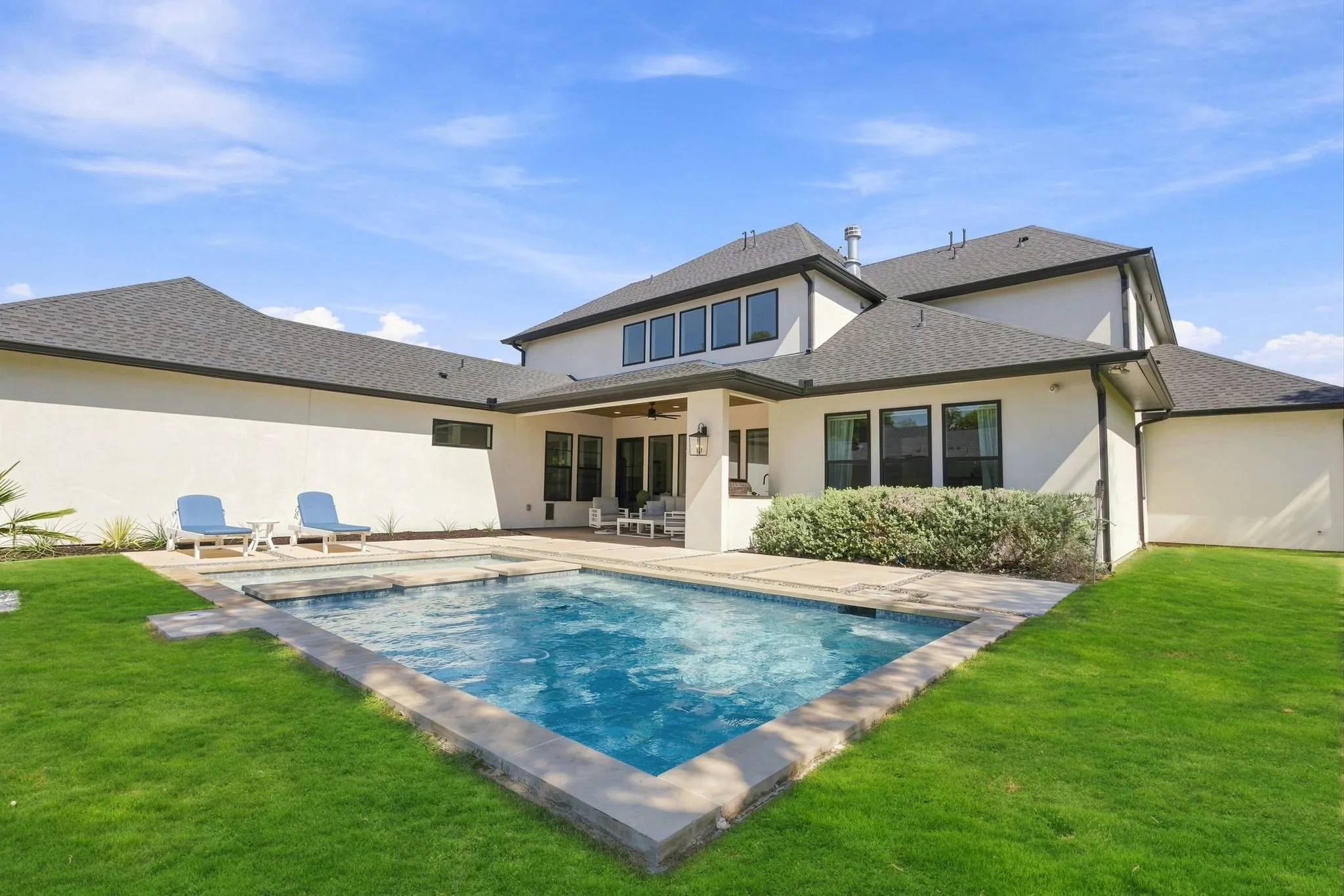 Expansive backyard featuring a rectangular swimming pool, integrated spa, and a covered patio with recessed lighting