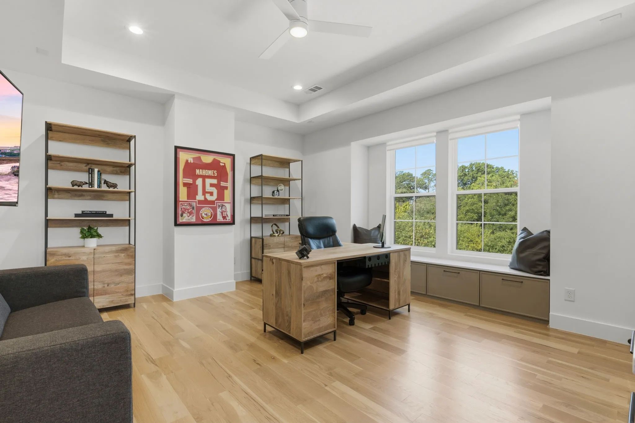 Light wood-finish flooring, recessed lighting, ceiling fan, large windows, and a built-in window bench with storage