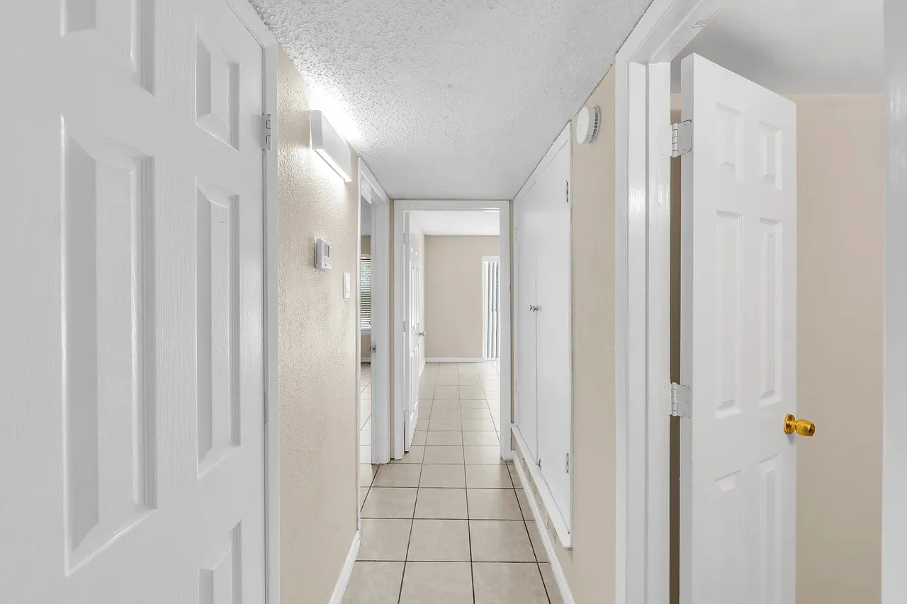 Hallway featuring tile flooring, white six-panel doors, and a built-in storage cabinet