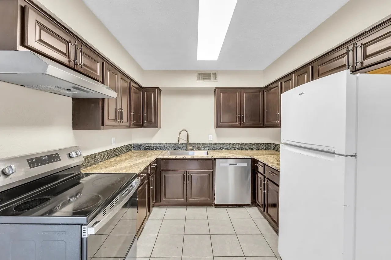 Kitchen featuring dark wood-finish cabinetry, light-toned countertops, a tile backsplash, and a ceramic tile floor