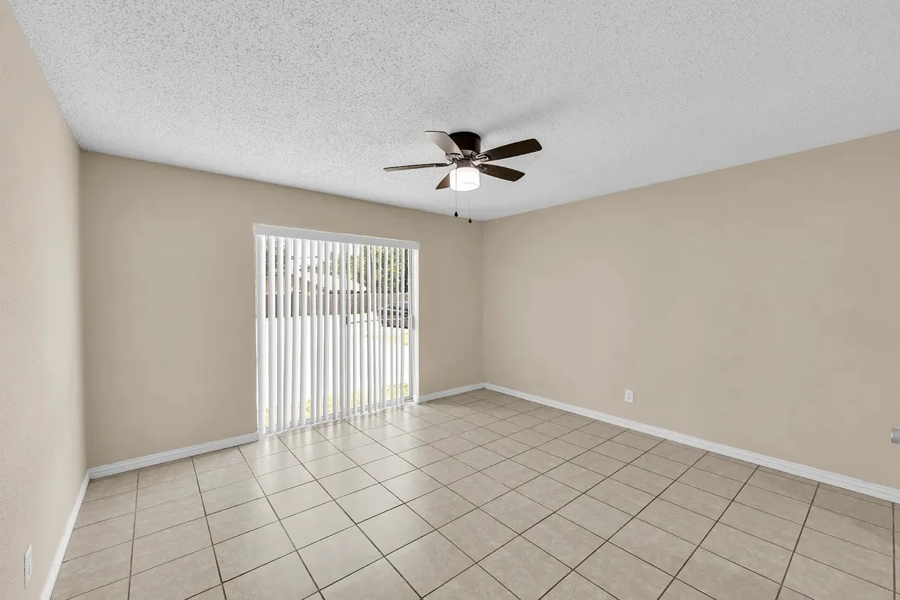 Vaulted ceiling with a ceiling fan, sliding glass door with vertical blinds, and square tile flooring