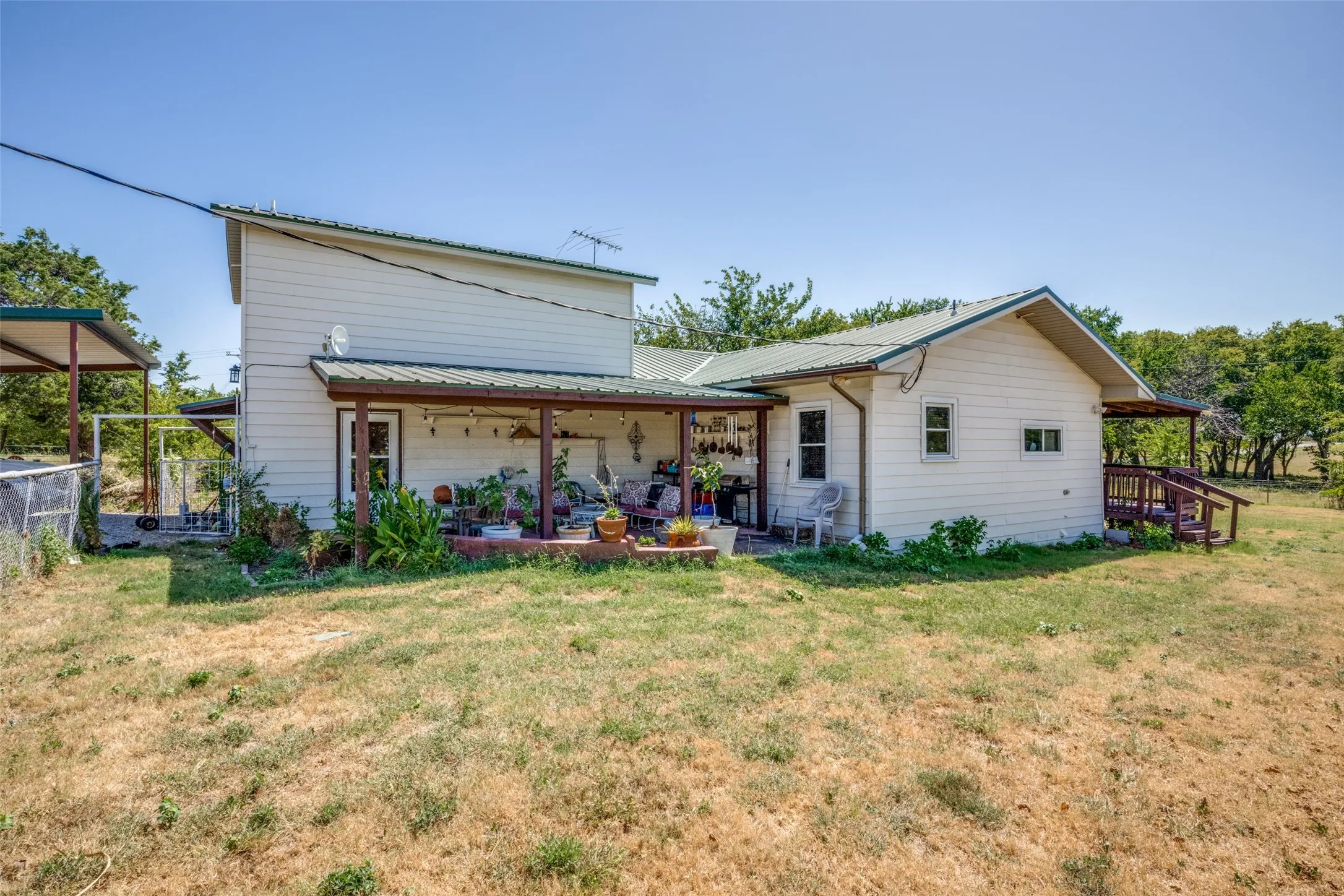 Rear exterior featuring a covered porch, metal roofing, wood siding, and a ramp entrance